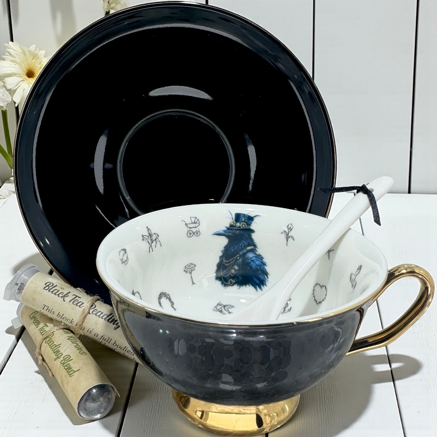 Tea cup with decorative interior, black saucer, and tea packaging on a white surface.
