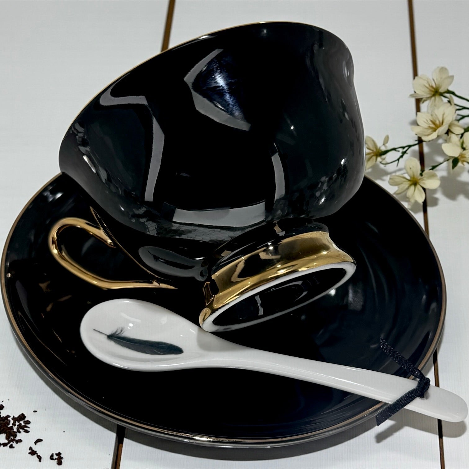 Black ceramic cup and saucer set with gold accents on a white background