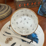 Teacup with decorative patterns on a saucer with similar designs, placed on a wooden surface.