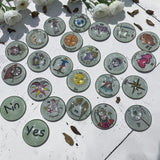 Complete set of 22 Major Arcana tarot charm casting coins with hand-drawn designs under glass dome tops and smooth metal backing plates displayed on a white surface