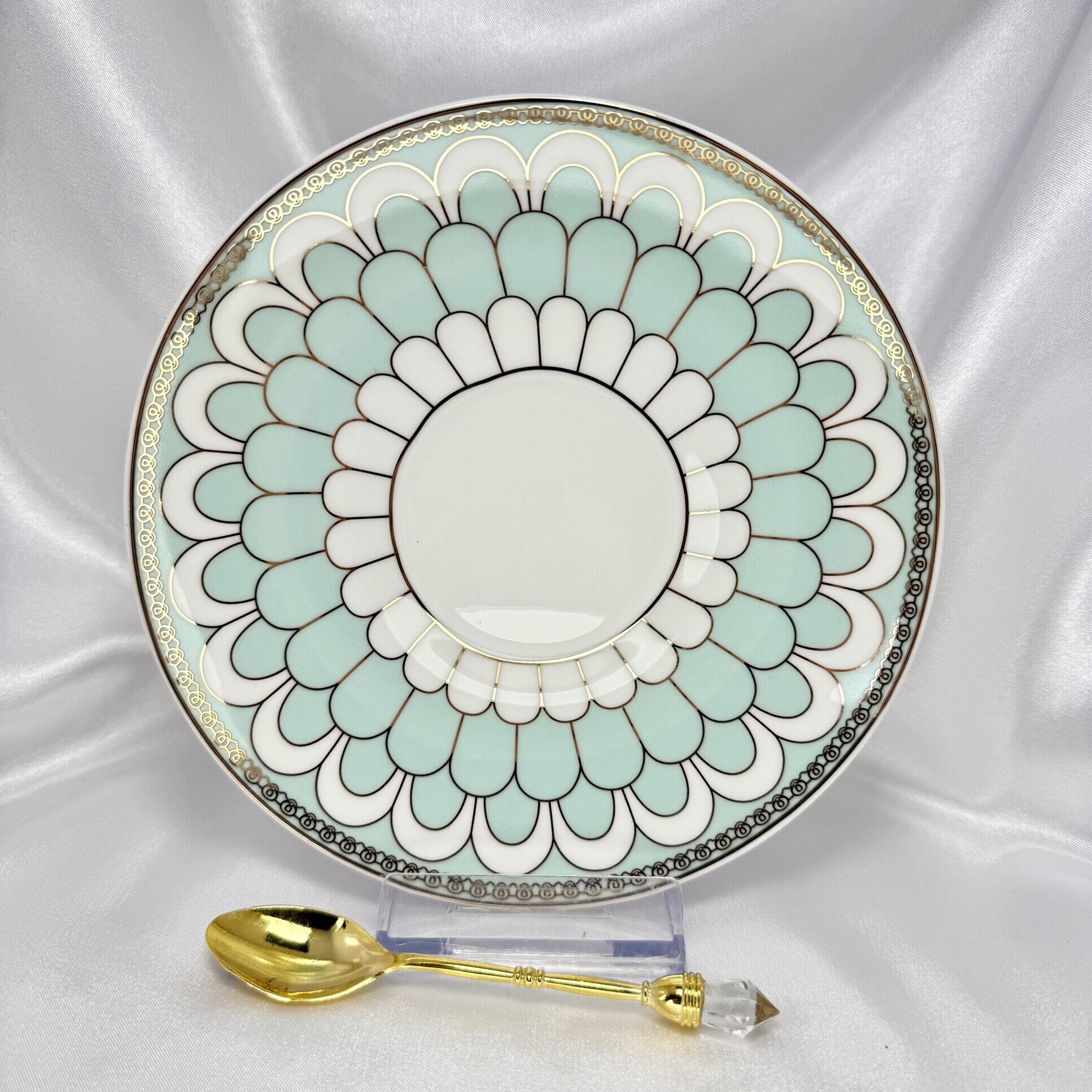 Porcelain saucer with mint green and white scalloped pattern, gold trim, displayed with an ornate gold teaspoon.