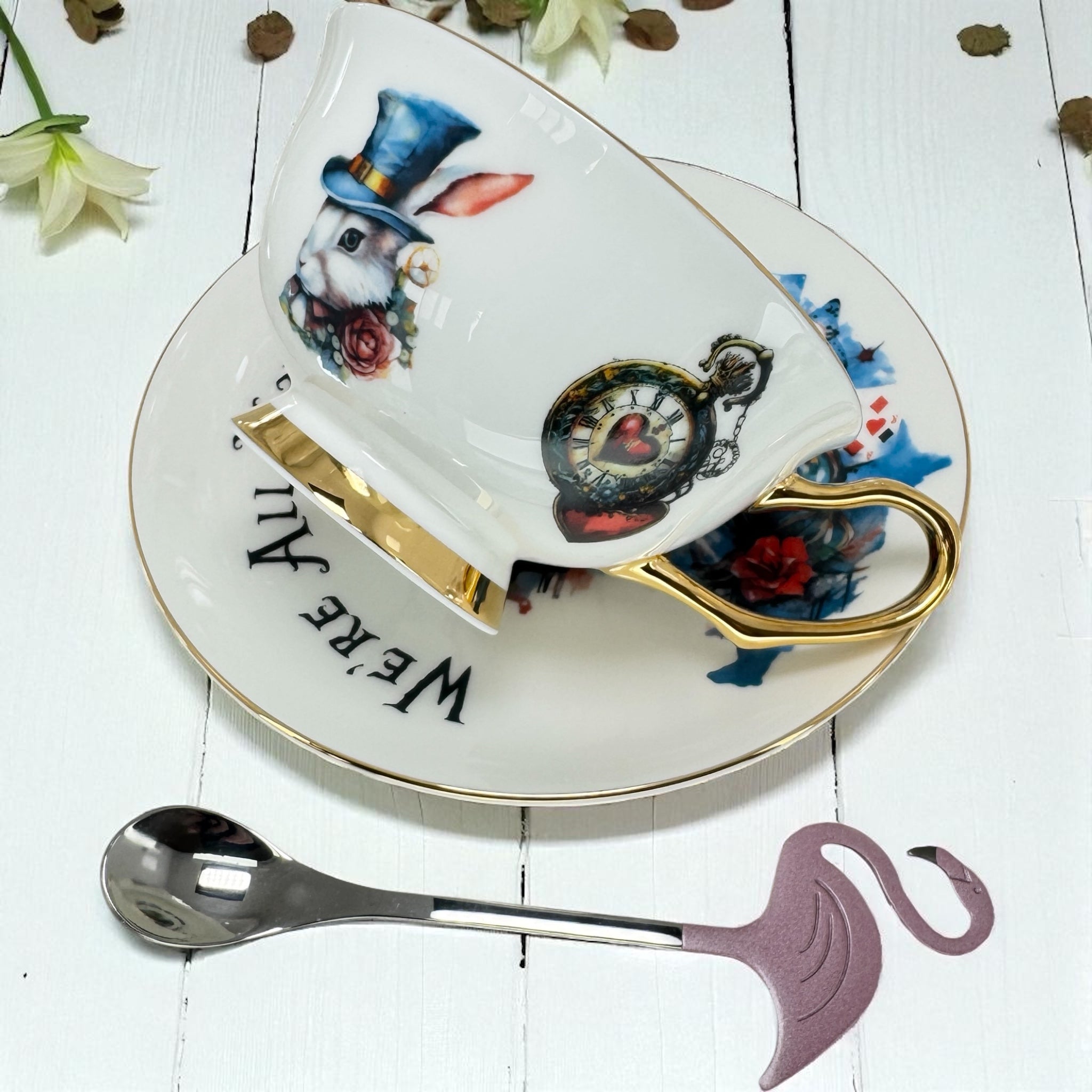 Decorative teacup and saucer with rabbit and clock design on a white wooden surface.