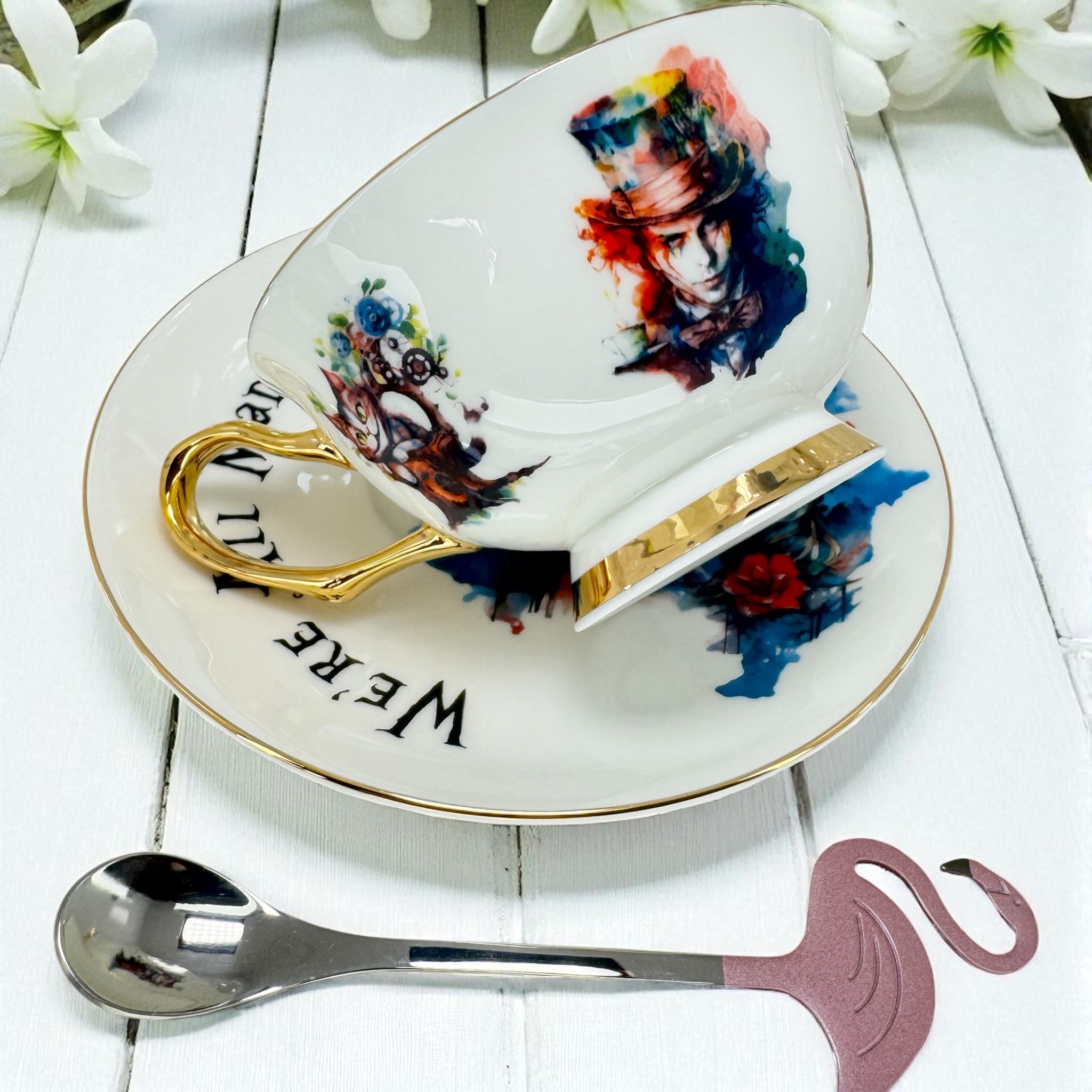 Decorative teacup set with artistic design on a white surface with flowers.