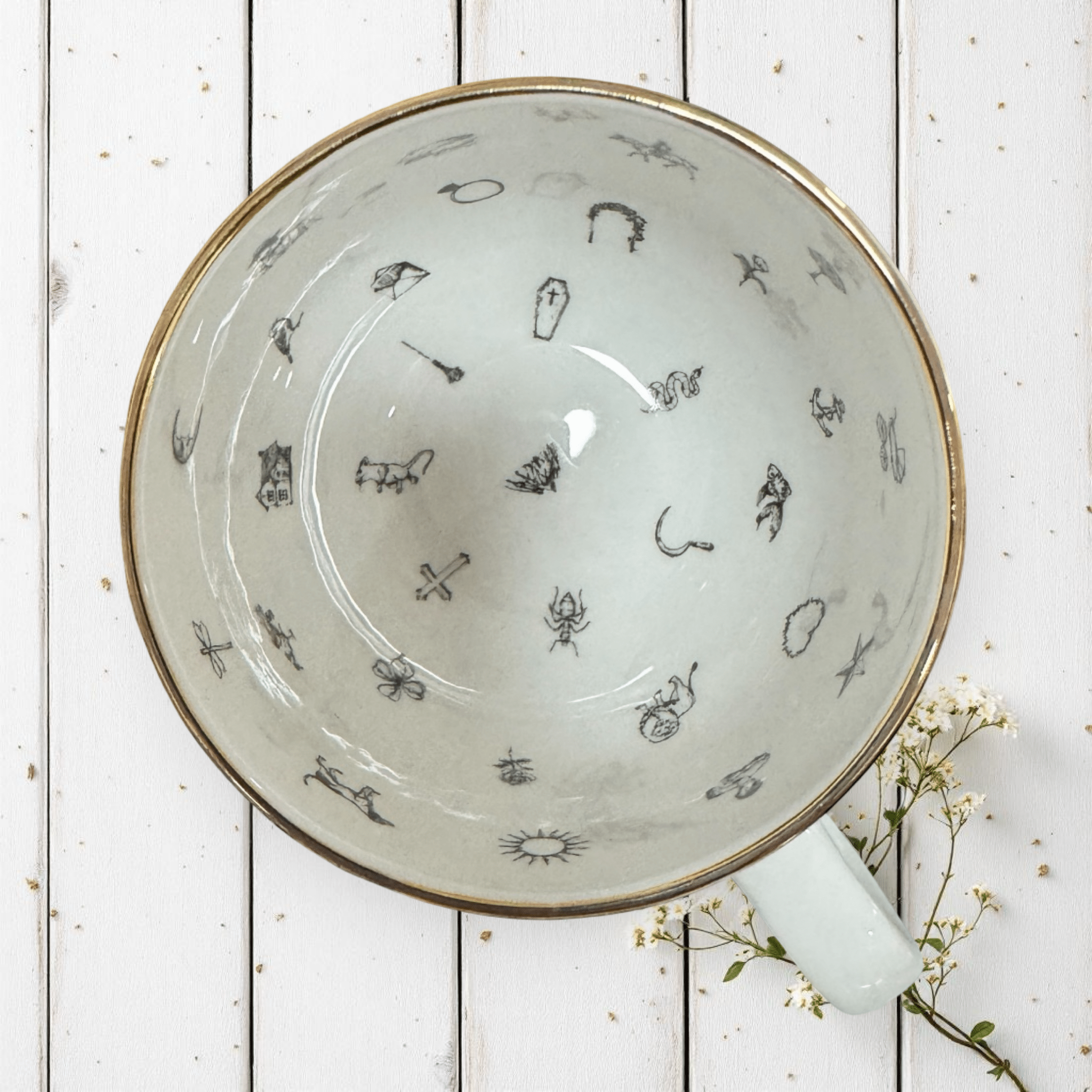 Woodland Fairy Elf Tea Reading Set — inside view of gold tasseography teacup showing Lenormand symbols in black line art on white wooden surface | Tea Leaf Reader