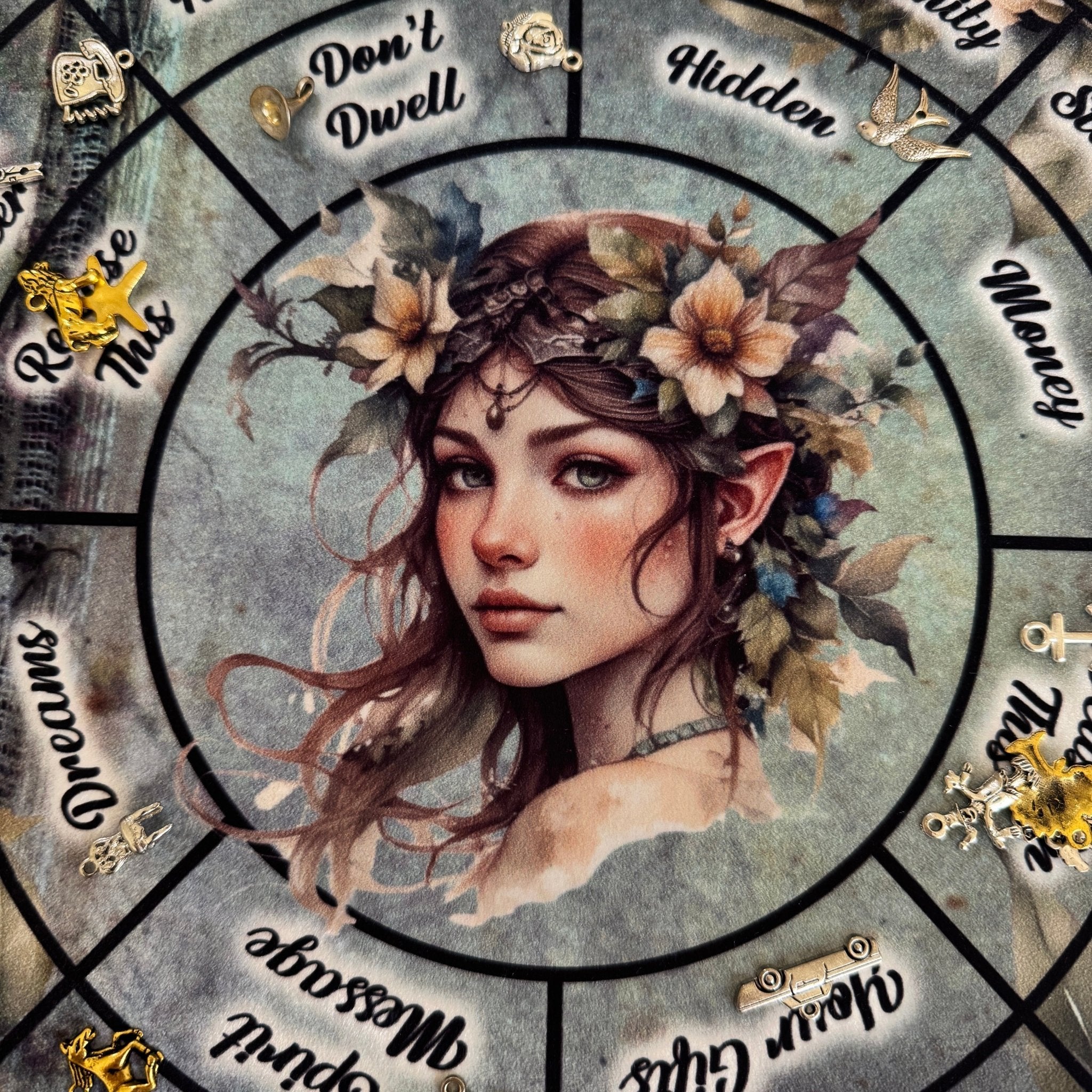 Close up of the central feminine elf figure with floral crown on a grey textured divination mat.