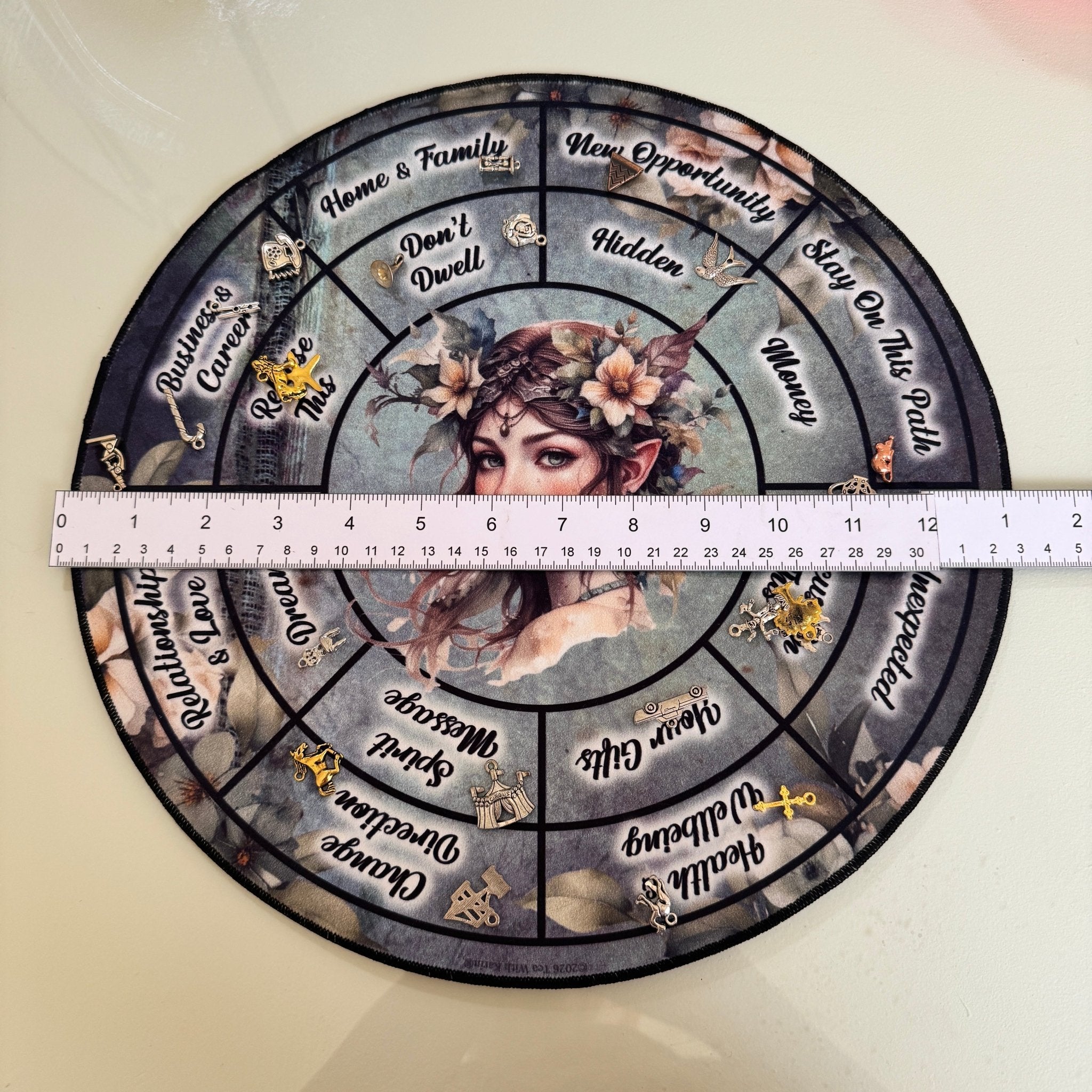 Top down view of the circular charm casting mat with a ruler showing a diameter of approximately 30 centimetres.