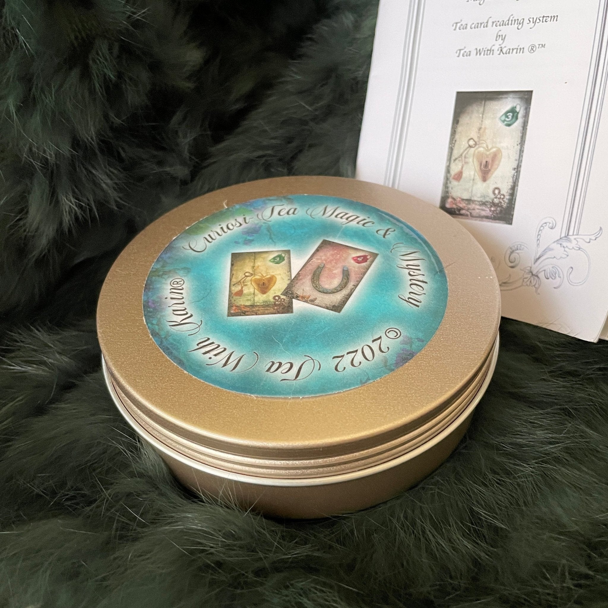 Discover the Curiosi-Tea Oracle Kit – a compact and enchanting tool for tea leaf divination. This unique set includes 18 thoughtfully designed cards, each adorned with symbolic imagery to guide your readings. Accompanied by a selection of charms, the kit offers a tactile dimension to your divination practice. Housed in a sleek gold tin, it’s perfect for on-the-go insights or intimate sessions at home. 